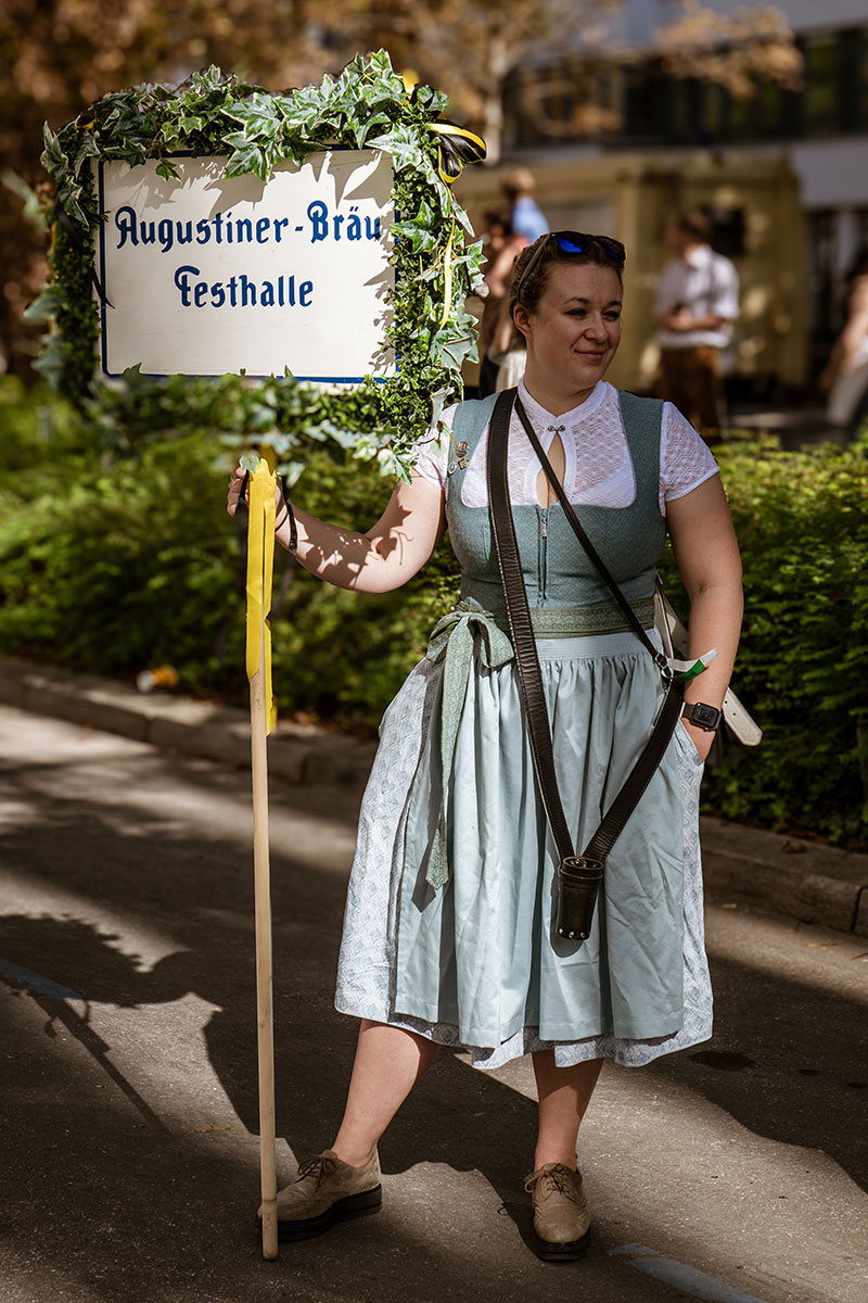 Frau im Dirndl mit Schild der Augustiner-Festhalle beim Einzug der Wiesnwirte